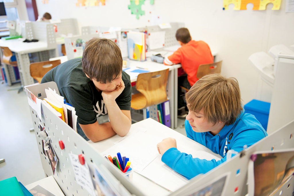 zwei Schüler arbeiten kooperativ an einer Aufgabe an einem persönlichen Arbeitsplatz im Schulzimmer